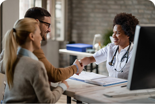 Casal feliz apertando a mão de médica após consulta na clínica, com foco na profissional